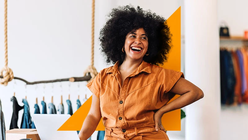 A business owner in a clothing shop, with teal and orange geometric branding.