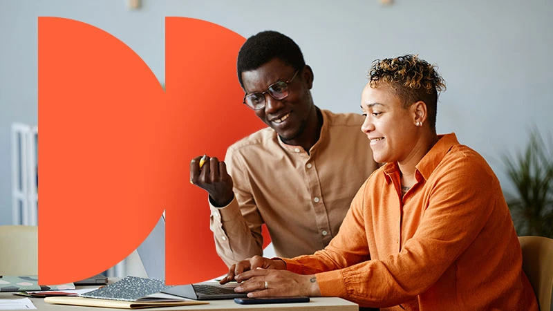 Two people collaborating at a laptop, with orange geometric branding.
